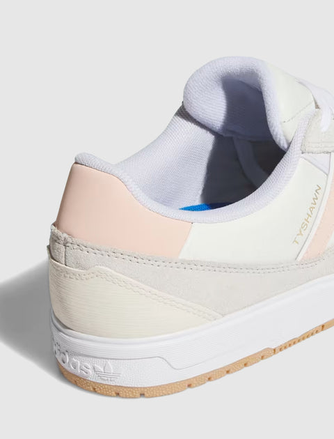 Close-up of a white and pink low-top sneaker with beige suede and textured sole
