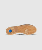 Gum sole of a sneaker with textured tread and blue circular accent on white background