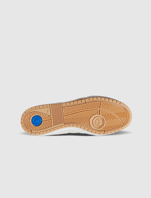 Gum sole of a sneaker with textured tread and blue circular accent on white background