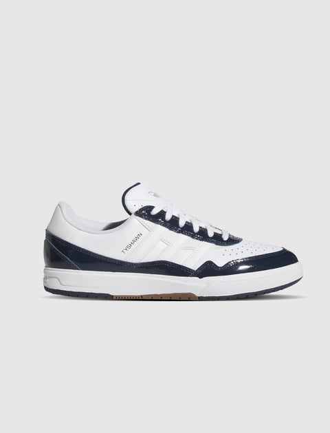 Low-top white and navy sneaker with green accents, perforated toe, and TYSHWN lettering.
