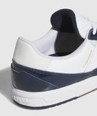 Close-up of white and navy low-top sneaker with gold 'TYSHAWN' text and textured sole