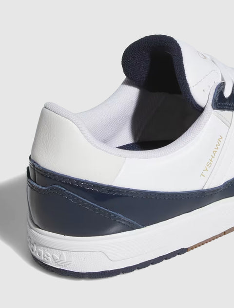 Close-up of white and navy low-top sneaker with gold 'TYSHAWN' text and textured sole