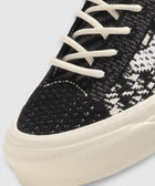 Close-up of black and white woven sneaker with white laces and textured rubber sole