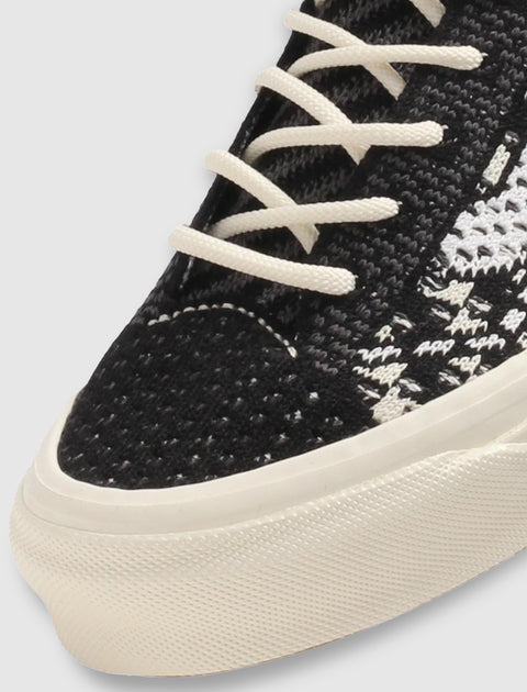 Close-up of black and white woven sneaker with white laces and textured rubber sole