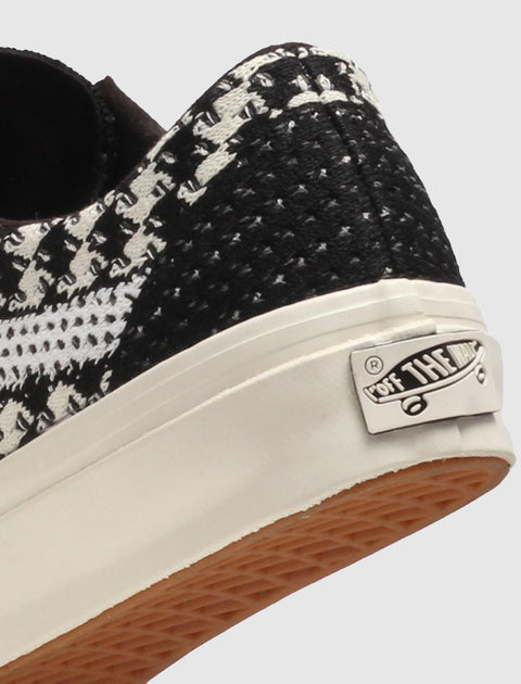 Close-up of black and white woven sneaker heel with logo patch and gum outsole