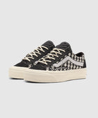 Black and white low-top sneakers with knit houndstooth pattern and white laces on white background
