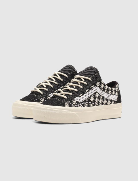 Black and white low-top sneakers with knit houndstooth pattern and white laces on white background
