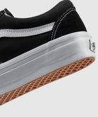 Black and white low-top sneaker with white stitching and gum sole on a plain background