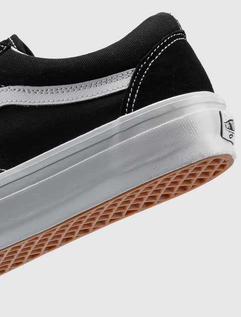 Black and white low-top sneaker with white stitching and gum sole on a plain background