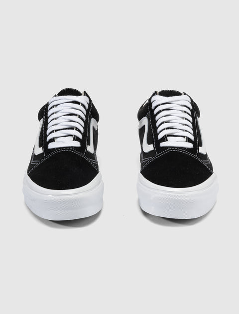Pair of black and white low-top sneakers with white laces and side stripe on plain background
