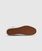 Closeup of black and white sneaker with brown waffle-pattern rubber sole on white background
