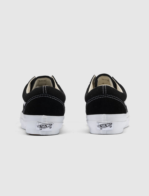 Black and white low-top sneakers with white stitching, viewed from the back on a plain background