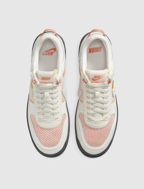 Top view of white and orange mesh low-top sneakers with Nike and UNION branding