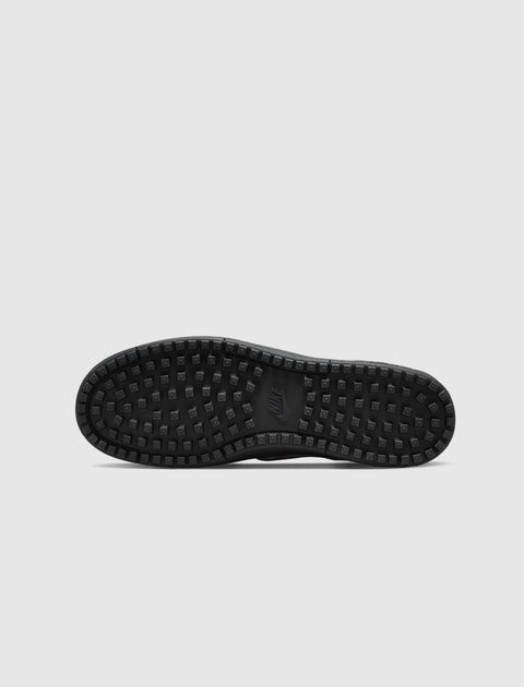 Black sneaker outsole with square grippy tread pattern on a plain background