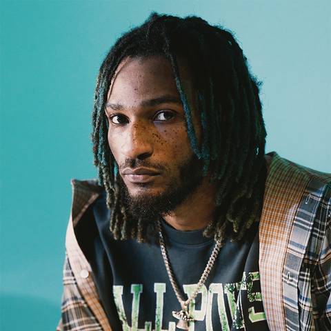Portrait of man in streetwear with plaid shirt, graphic tee, and chain necklace, teal background