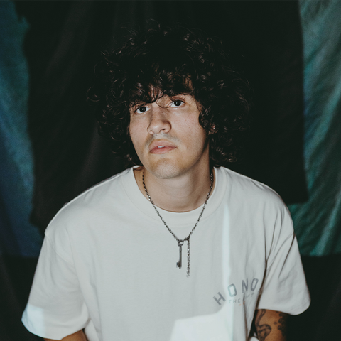 Man in white streetwear t-shirt and key necklace, curly hair, casual apparel style