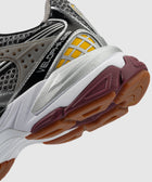 Close-up of athletic sneaker with silver, yellow, black mesh upper and gum outsole
