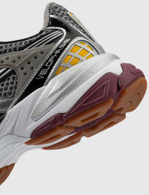 Close-up of athletic sneaker with silver, yellow, black mesh upper and gum outsole