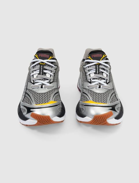 Pair of silver mesh and leather sneakers with black, yellow, and gum accents on a white background