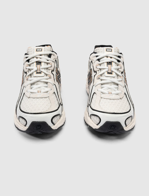 Front view of white mesh and leather sneakers with black accents and N logo on soles
