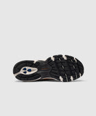 Black and white New Balance sneaker sole with textured grip and blue accents on gray background
