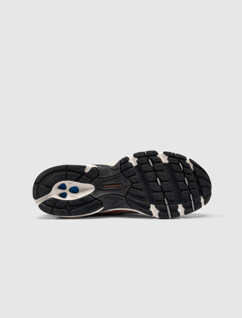 Black and white New Balance sneaker sole with textured grip and blue accents on gray background