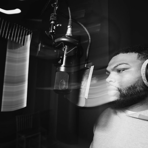 Man wearing headphones recording vocals at a studio microphone, black and white streetwear style