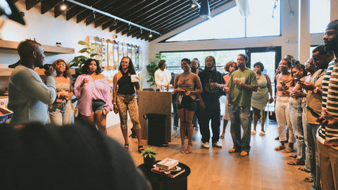 Diverse group of people at a streetwear store event, listening to speaker indoors