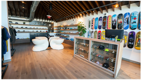 Modern men's streetwear and sneaker shop interior with skateboard wall display, hats, and apparel.