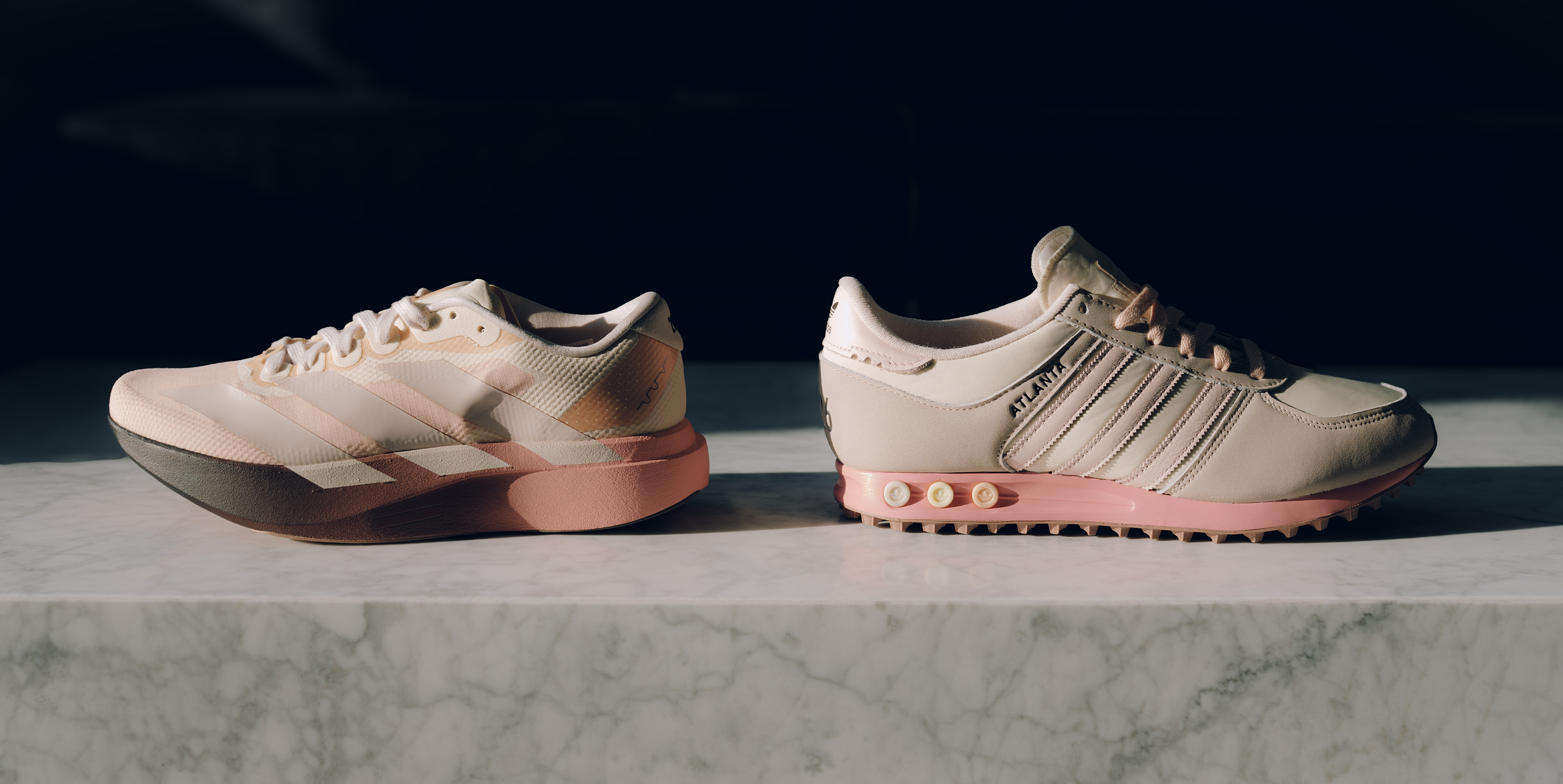 Two pink men's streetwear sneakers with white accents displayed on marble surface