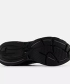Black New Balance sneaker outsole with textured grip and pink logo on white background