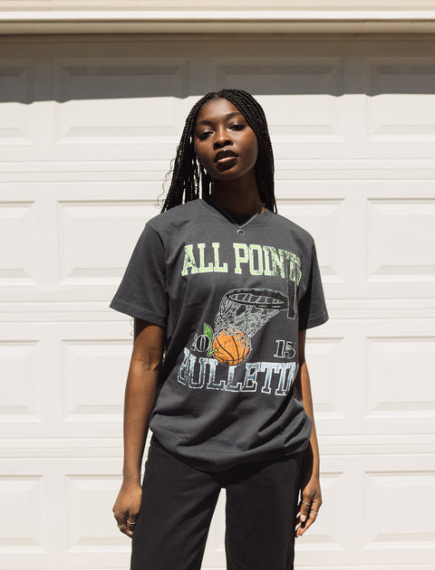 Woman wearing a black streetwear graphic t-shirt with basketball hoop print outdoors