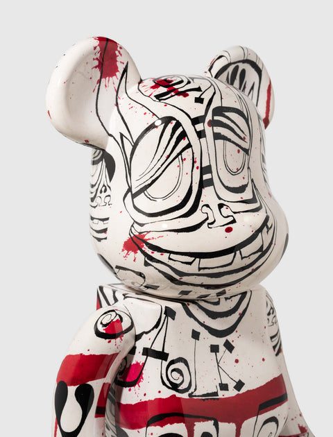 Close-up of art toy bear figure with graffiti-style black and red abstract face design