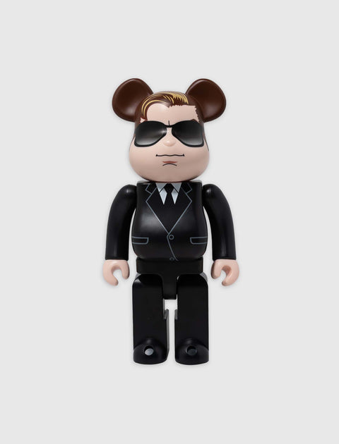 Bearbrick collectible toy figure in a black suit with sunglasses and bear ears on a plain background