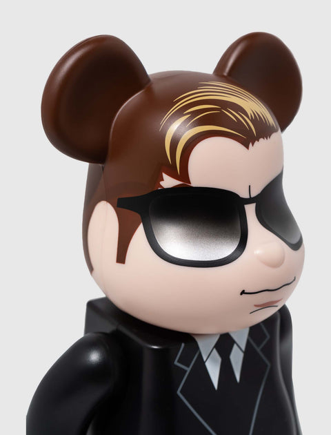 Bearbrick collectible figure with brown ears, sunglasses, and black suit on white background