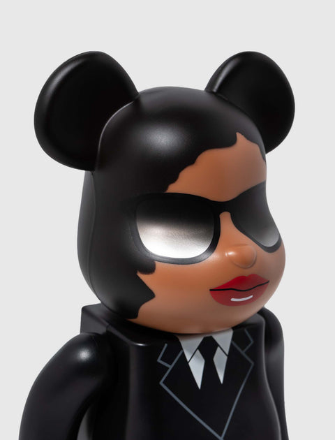 Designer toy bear figure with black suit, sunglasses, red lips, and mouse ears