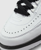 Close-up of white leather sneaker with black laces and perforated detailing