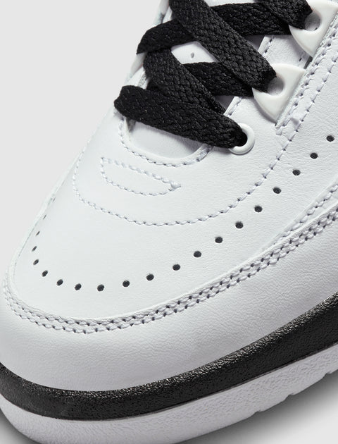 Close-up of white leather sneaker with black laces and perforated detailing