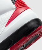 Close-up of a white, black, and red sneaker heel with textured leather and rubber sole