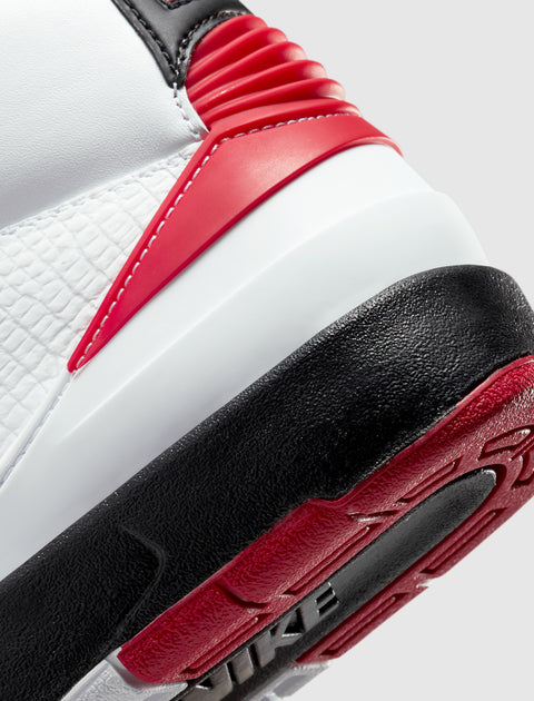 Close-up of a white, black, and red sneaker heel with textured leather and rubber sole