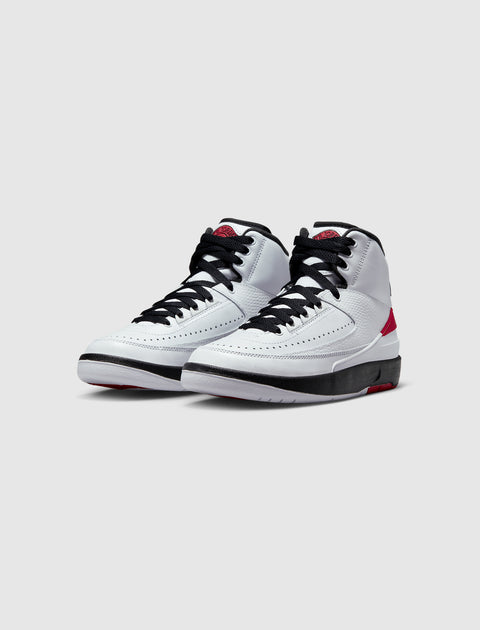 White and red high-top sneakers with black laces on a simple gray background
