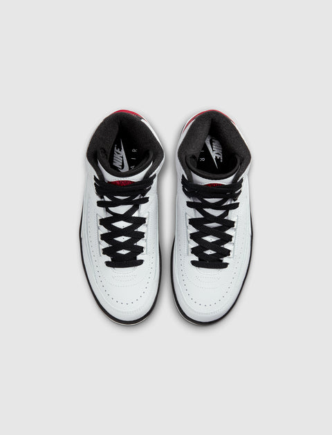 White high-top sneakers with black laces and red accents, viewed from above.