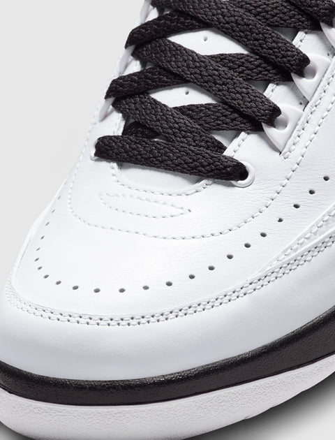 Close-up of white leather sneaker with black laces and perforated toe box