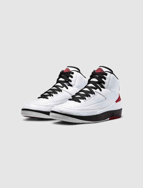 White and red high-top sneakers with black laces on a plain background