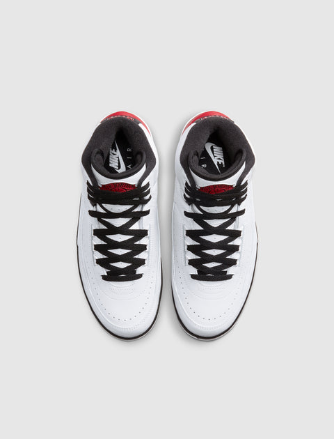 White and red high-top sneakers with black laces, viewed from above on gray background.