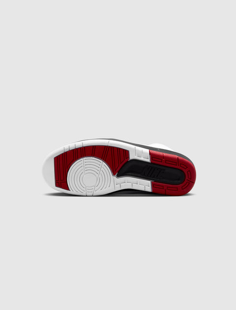 Bottom view of sneaker with red, white, and black sole on grey background