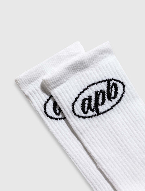Pair of white ribbed crew socks with black oval apb logo on cuffs