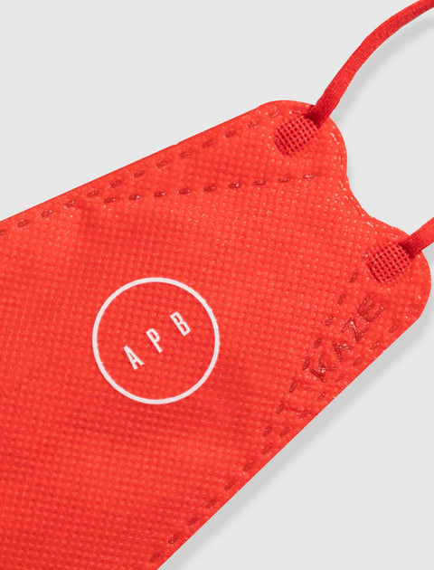 Red textured face mask with white APB logo and ear loops, close-up view