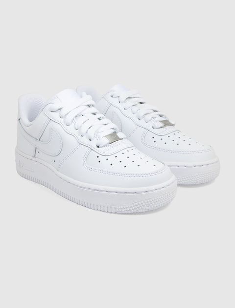 Pair of white leather low-top sneakers with perforated toe and thick rubber sole on gray background