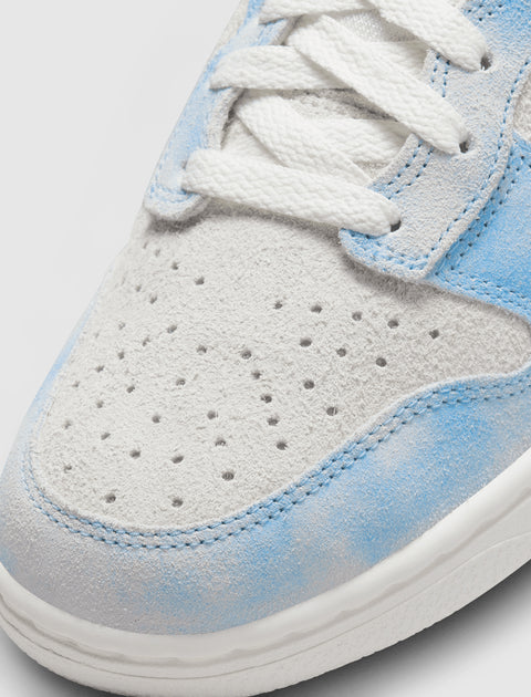 Close-up of suede light blue and white sneaker toe with white laces and perforations